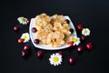 Homemade dessert for children from toffee, butter and corn sticks on a white plate, decorated with daisies with ladybirds and