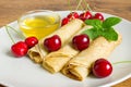 Homemade dessert. Fried pancakes with honey. Crepe with black cherry on white plate background.