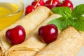 Homemade dessert. Fried pancakes with honey. Crepe with cherry on white plate background.