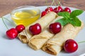 Homemade dessert. Fried pancakes with honey. Crepe with cherry on white plate background.