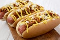 Homemade Detroit style chili dog on a rustic wooden board on a white wooden background, side view. Close-up Royalty Free Stock Photo