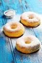 Homemade donuts sprinkled with icing sugar on a wooden blue background