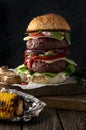 Homemade double burger with sesame seed bun, grilled beef, sauce, vegetables and cheese garnished with roasted mushrooms and corn Royalty Free Stock Photo