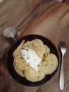 Homemade dumplings with sour cream in a black plate on a wooden table. Dumplings with hand-sculpted potato filling. Soft