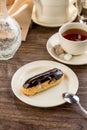 Homemade eclair dessert with chocolate sauce and cup of tea on wooden table Royalty Free Stock Photo
