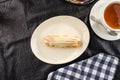 Homemade eclair dessert with vanilla sauce on white plate with cup of tea on the table Royalty Free Stock Photo
