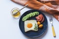 Homemade egg in a hole with toast bread and colorful vegetables on a blue ceramic plate on white table with yellow fork Royalty Free Stock Photo