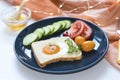 Homemade egg in a hole with toast bread and vegetables on a blue ceramic plate with honey on a white background, close up, indoor Royalty Free Stock Photo