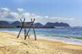 Homemade empty rope swing on a deserted beach against the background of the sea and blue sky with clouds. Royalty Free Stock Photo