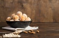 Homemade energy balls of raw carrots, dried fruits, oatmeal and nuts in a brown bowl on a wooden background.