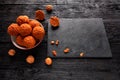 Homemade energy balls with walnuts, peanuts, honey and banana in a white porcelain plate on a black wooden background near with Royalty Free Stock Photo