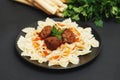 Homemade Farfalle Pasta with Meatballs and Sauce on Black Plate. Healthy Food.