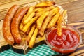 Homemade fast food, portion of french fries, ketchup, grilled sausages, on wooden board. Royalty Free Stock Photo