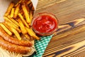 Homemade fast food, portion of french fries, ketchup, grilled sausages, on wooden board. Royalty Free Stock Photo