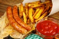 Homemade fast food, portion of french fries, ketchup, grilled sausages, on wooden board. Royalty Free Stock Photo