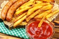 Homemade fast food, portion of french fries, ketchup, grilled sausages, on wooden board. Royalty Free Stock Photo