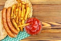 Homemade fast food, portion of french fries, ketchup, grilled sausages on wooden board. Royalty Free Stock Photo