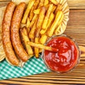 Homemade fast food, portion of french fries, ketchup, grilled sausages on wooden board. Royalty Free Stock Photo