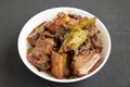 Homemade Filipino Adobo Pork in a white bowl on a black surface, side view. Close-up