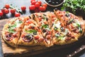 Homemade flatbread pizza sliced on wooden cutting board