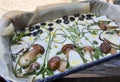 Homemade focaccia bread with Boletus Edulis porcini mushroom decorated with aromatic herbs and black olives.