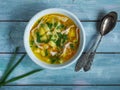 Homemade food, chicken soup with potatoes, pasta and green onions in a deep plate on a blue wooden table Royalty Free Stock Photo