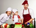 Homemade food. Family preparing dinner in kitchen. Little son and parents in uniform and chef hat. Royalty Free Stock Photo