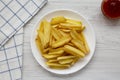 Homemade french fries with sour-sweet sauce on a white plate on a white wooden table, top view. Flat lay, overhead, from above. Royalty Free Stock Photo