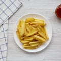 Homemade french fries with sour-sweet sauce on a white plate on a white wooden table, top view. Flat lay, overhead, from above. Royalty Free Stock Photo