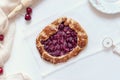 Homemade french fruit galette with cherry on a white table with rolling pin and cutter, above vantage point photography Royalty Free Stock Photo