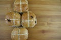 Freshly baked warm hot cross buns laid on a wood cutting board with space