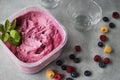 Homemade fresh berry ice cream with basil in  plastic box on gray background. Pink sorbet Royalty Free Stock Photo