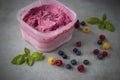 Homemade fresh berry ice cream with basil in  plastic box on gray background. Pink sorbet Royalty Free Stock Photo
