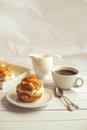 Homemade fresh cream puff with whipped cream and apricots, cup of coffee and milk jug. Royalty Free Stock Photo