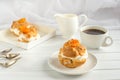 Homemade fresh cream puff with whipped cream and apricots, cup of coffee and milk jug. Toning. Royalty Free Stock Photo