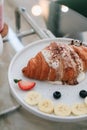 Homemade fresh croissants with sweet topping banana, cream and strawberry. Royalty Free Stock Photo