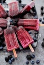 Homemade fresh frozen blueberry and blackberry popsicles on black plate with ice sitting on stone Royalty Free Stock Photo