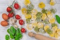 Homemade fresh Italian ravioli pasta on white wood table with flour, basil, tomatoes,background,top view Royalty Free Stock Photo