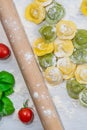 Homemade fresh Italian ravioli pasta on white wood table with flour, basil, tomatoes,background,top view Royalty Free Stock Photo