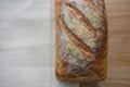 Close up food image of a fresh home made artisan white bread loaf on a cream cloth and wood board background