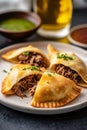 Homemade freshly baked Argentinian beef empanadas turnover pies on a plate served with chimichurri sauce. Latin American cuisine