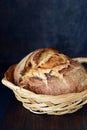 Homemade Freshly Baked Country Bread  in a basket made from wheat and whole grain flour on a dark background. Royalty Free Stock Photo