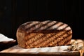 Homemade freshly baked whole grain bread made from rye and wheat sourdough, selective focus on a loaf of bread. Dark mood.