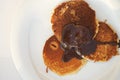 Homemade, freshly prepared pancakes drenched in chocolate on a white plate on a table with a white tablecloth. Place for your text