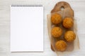 Homemade fried Arancini on a rustic wooden board, blank notepad on a white wooden background, top view. Flat lay, from above, Royalty Free Stock Photo