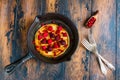 Homemade fried pancakes on a black cast iron skillet. Above are berries, raspberries, cranberries and blackberries.