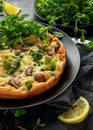 Homemade Frittata with mushrooms, broccoli, feta cheese, green peas and bacon on black plate