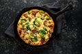 Homemade Frittata with mushrooms, broccoli, feta cheese, green peas and bacon on cast iron skillet