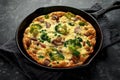 Homemade Frittata with mushrooms, broccoli, feta cheese, green peas and bacon on cast iron skillet