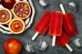 Homemade frozen blood orange natural juice alcoholic popsicles - paletas - ice pops. Overhead, flat lay, top view.